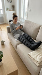 Une femme se détend sur le canapé avec les bottes de massage